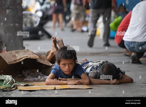 Street children in Cebu City,Philippines on the sidewalk lying on cardboard which they use as ...