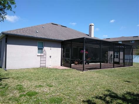 The Back Of A House With A Screened In Porch And Covered Patio Area Next To It