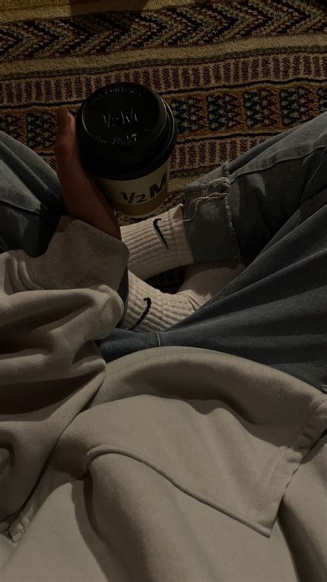 A Person Laying On The Floor With Their Feet Up Holding A Coffee Cup In