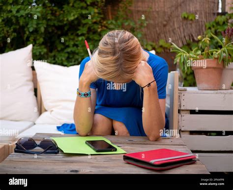 Adult Depressed Blonde Woman Hunched Over On Her Hands Sitting In The Garden Stock Photo Alamy