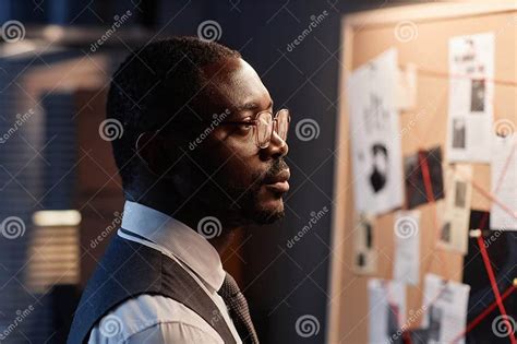 Dramatic Black Detective Looking At Evidence Board In Office