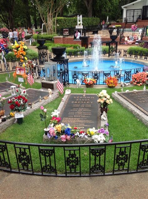 A Memorial Sits In The Middle Of A Grassy Area With Flowers And Flags On It