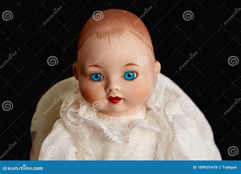 Closeup Of Old Porcelain Doll With Blue Eyes On Black Background Stock