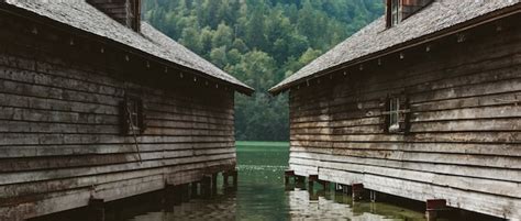 Dos casas grises de madera en el agua en las montañas alpinas boscosas