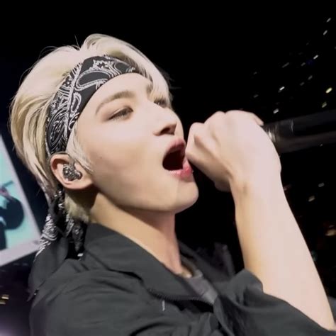 A Male Singer In A Black Shirt And Bandana Singing Into A Microphone