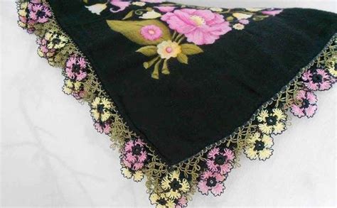 A Black Bandana With Pink Flowers And Gold Trimmings Sits On A White