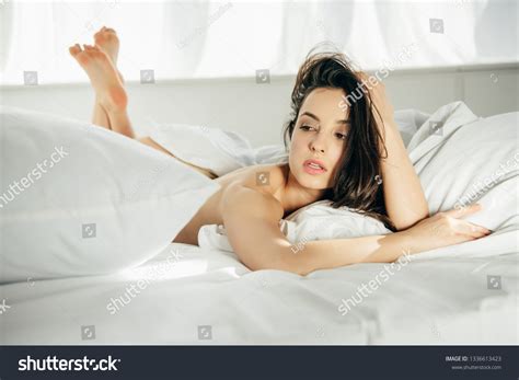 Стоковая фотография 1336613423 Nude Brunette Girl Lying On Bed