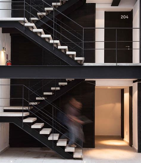 A Man Is Walking Down The Stairs In A Modern Building With Black Walls