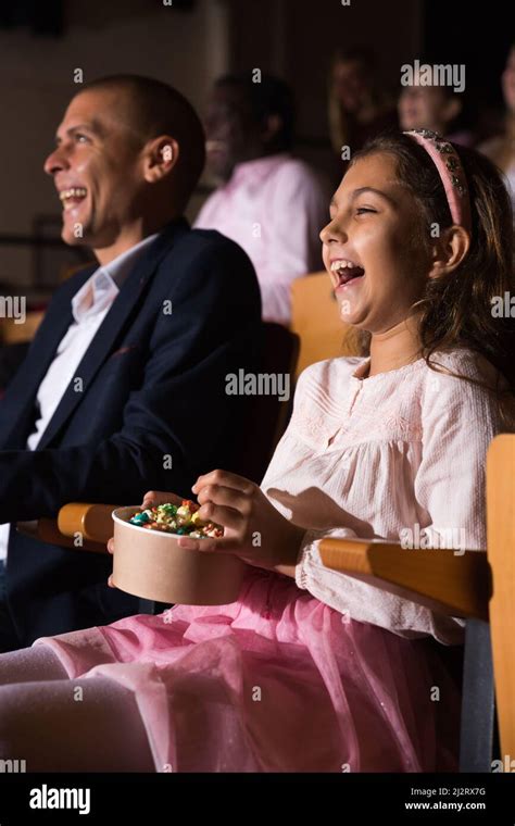 Tween Girl Laughing While Watching Comedy At Movie Theater Stock Photo