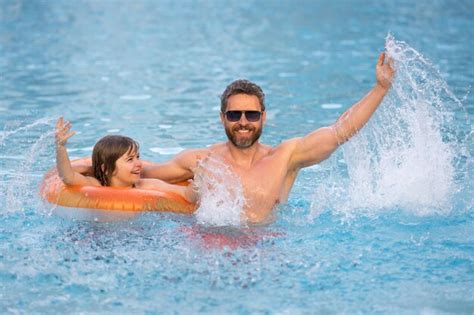 Niño salpica agua en la piscina padre e hijo nadando y chapoteando en