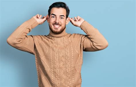 Joven Hispano Con Ropa Informal Sonriendo Tirando De Las Orejas Con Los