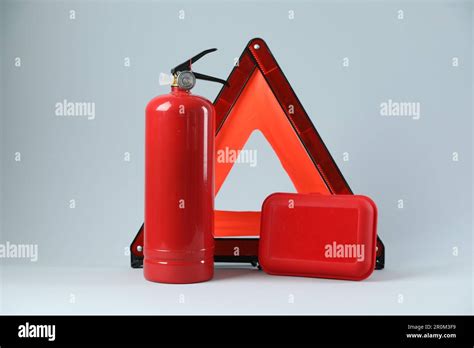 Emergency Warning Triangle Red Fire Extinguisher And First Aid Kit On Light Grey Background