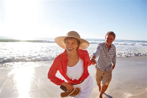 Full Of Vitality A Mature Couple Enjoying A Late Afternoon Walk On The Beach Stock Photo