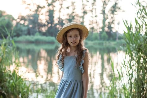 Una Chica Con Vestido Azul Y Sombrero De Paja Se Encuentra En La Orilla