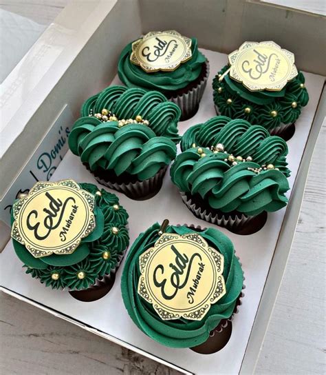 Cupcakes With Green Frosting And Gold Decorations In A Box On A Table