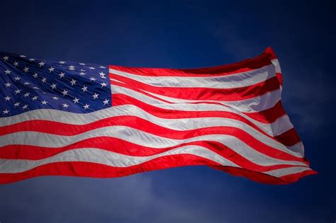 Premium Photo Low Angle View Of American Flag Waving Against Blue Sky