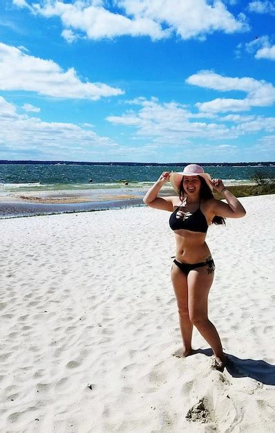 Retrato de una mujer joven en bikini de pie en la playa en un día
