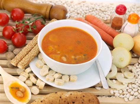 Un Plato De Sopa Con Una Cuchara Junto A Un Poco De Pan Y Tomates