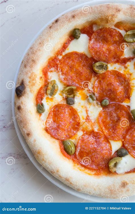 Whole Round Neapolitan Pepperoni Pizza Served On A Table Stock Photo