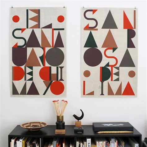 Two Abstract Paintings Hang On The Wall Above A Bookshelf