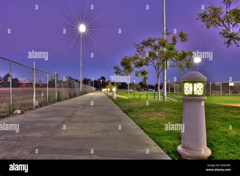 Public Park At Dusk With Lamps Along Sidewalk Stock Photo Alamy