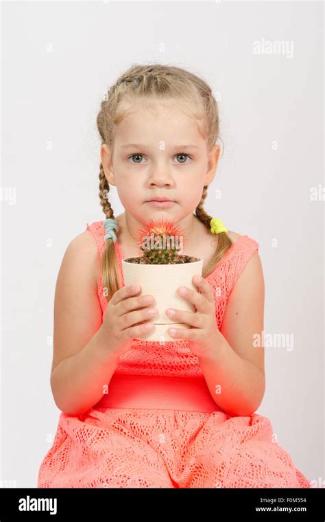 Four Year Girl Stands With A Cactus In A Pot Isolated On A Light