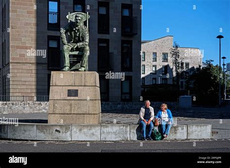 Elderly Couple Sitting Next To The Seated Statue Of Scottish Architect