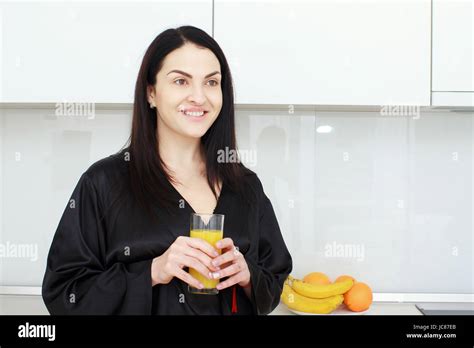 Beautiful Young Woman Holding Glass Of Orange Juice In The Kitchen