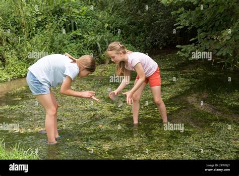 Two Young Girls Sisters Playing In A Stream Getting Wet Catching