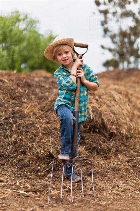 Boy Using Pitchfork In Haystack Stock Photo Dissolve