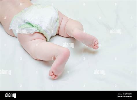 A Child In A Diaper Lies On White Bed Taking Care Of The Baby