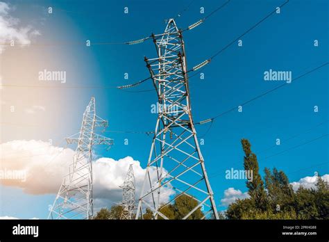 Low Angle View Of High Voltage Towers And Electric Cables Against Sunny