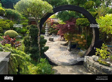 Japanese Style Garden With Moon Gate Rocks Shrubs And Trees Design By