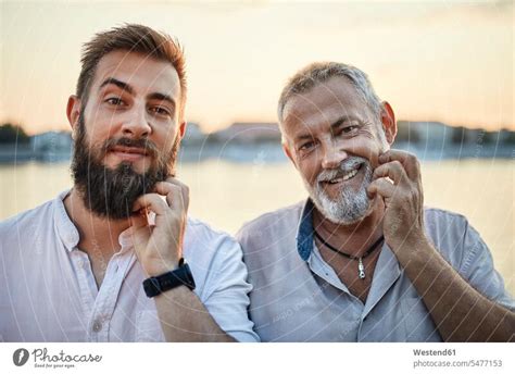 Portrait Of Smiling Father And Adult Son Scratching Their Beards A