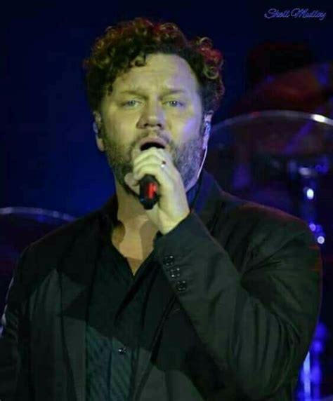 A Man Singing Into A Microphone On Stage