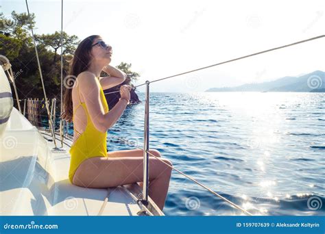 Attractive Young Woman In A Bright Yellow One Piece Swimsuit Sits On