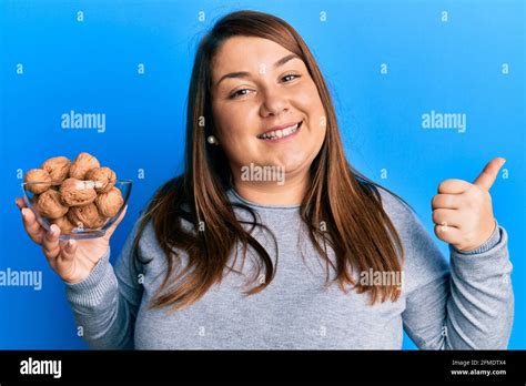 Beautiful Brunette Plus Size Woman Holding Bowl With Walnuts Pointing