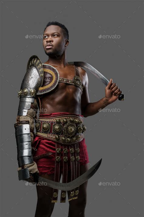 African Roman Gladiator With Twin Swords Isolated On Gray Stock Photo