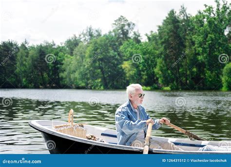 Serious Pensioner Looking Thoughtful While Rowing His Boat Stock Photo