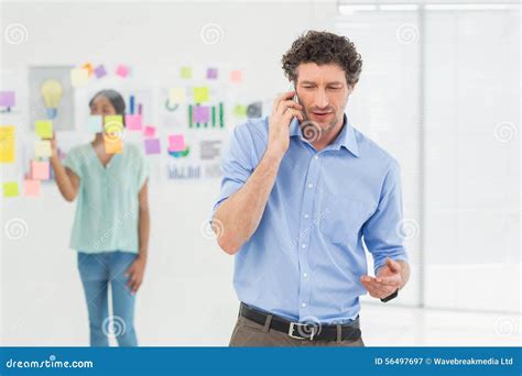 Businessman Having Phone Call While His Colleague Posing Stock Image