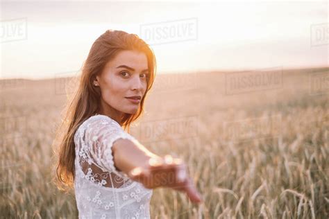 Woman Standing In Wheat Field With Outstretched Arm Stock Photo