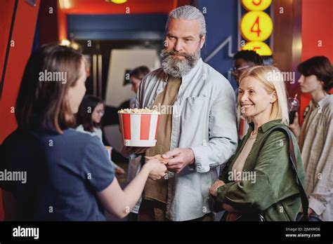 Modern Mature Couple Passing Their Tickets For Movie To Young Female