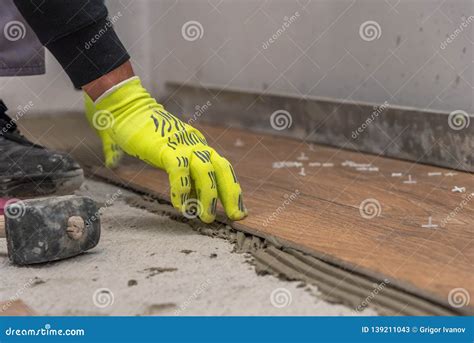 Worker Placing Ceramic Floor Tiles On Adhesive Surface Leveling With