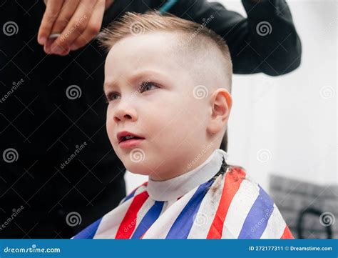 The Boy Kid Is Getting A Haircut In A Barbershop Hair Stylist Indoor