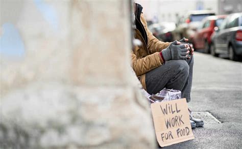 A Midsection View Of Homeless Beggar Man With A Carboard Sign Sitting