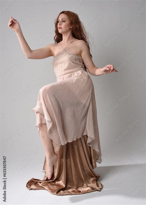 Full Length Portrait Of Beautiful Female Model With Long Brunette Hair Wearing A Creamy Pink