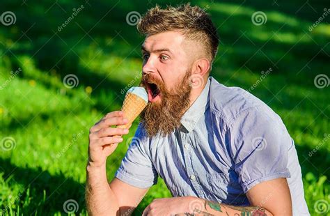 Man With Long Beard Enjoy Ice Cream While Sits On Grass Delicacy