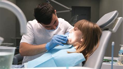 A Male Dentist Examines The Oral Cavity Of A Teenage Girl Using A