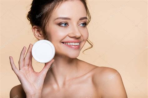 Modelo positivo con hombros desnudos sosteniendo crema cosmética