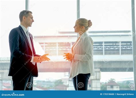 Business Man Stands And Discuss With Young Beautiful Woman In The Room